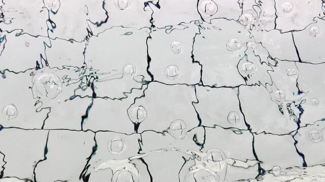 Water bubbles and ripples animate white tiled swimming pool floor
