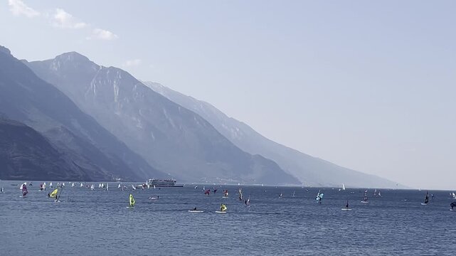 Windsurfers on Lake Garda with mountains in the background, Italy