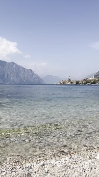Pebble beach and Lake Garda with swimmers in Malcesine, Italy