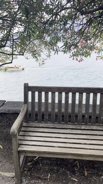 Scenic view of Lake Como with a wooden bench and white boat in the background, Italy