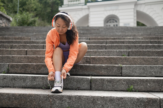 Portrait of fit young asian lady tie sneakers in the city. Female runner training in a urban area. Healthy lifestyle and sport concepts. workout outdoors, wearing sports outfit.