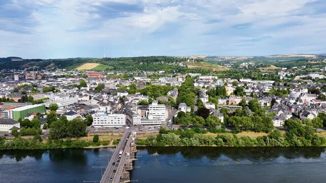 Luftbild von Trier mit der antiken R&ouml;merbr&uuml;cke &uuml;ber die Mosel, umgeben von Stadtarchitektur und gr&uuml;nen H&uuml;geln unter bew&ouml;lktem Himmel an einem Sommertag.