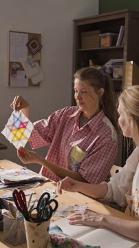 Vertical video of young adult Caucasian woman showing patchwork quilt block pattern to student during creative workshop. Clip is ideal for promoting craft classes or DIY hobby tutorials