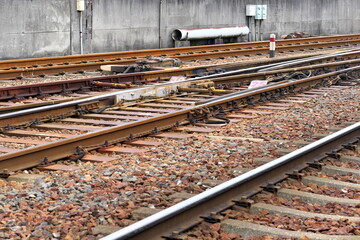 コンクリート壁沿いに続くバラスト軌道の線路とコンクリート枕木 © taka