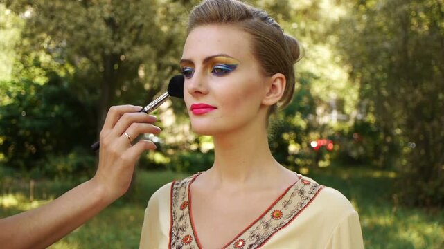 woman puts on face powder brush