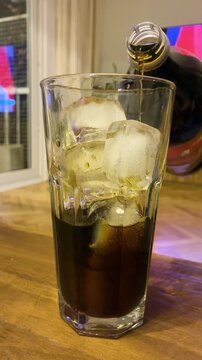 Close up of cold refreshing Fernet and cola cocktail in a glass with ice cubes and condensation, classic Argentine drink for a night out