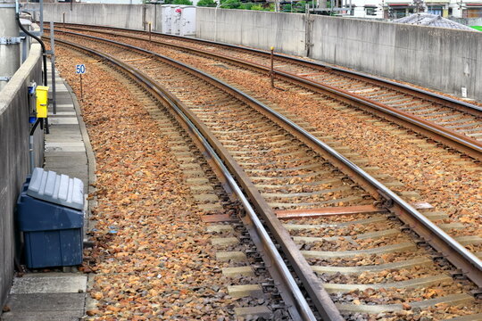 コンクリート壁沿いに続くバラスト軌道の線路とコンクリート枕木