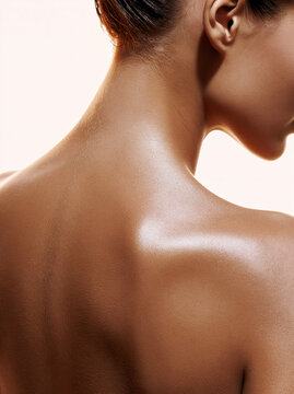 Nahaufnahme des gepflegten R&uuml;ckens einer Frau mit gl&auml;nzender Haut vor hellem Hintergrund. Beauty, Hautpflege, Wellness, K&ouml;rperpflege, Spa und nat&uuml;rliche Sch&ouml;nheit.