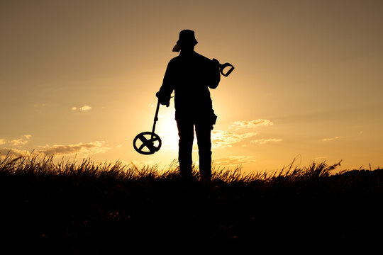 Sunlit Treasure Hunter with Shovel and Metal Detector Facing the Camera