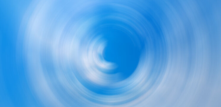 Abstract blue sky with white clouds spinning in a radial blur vortex circle pattern background