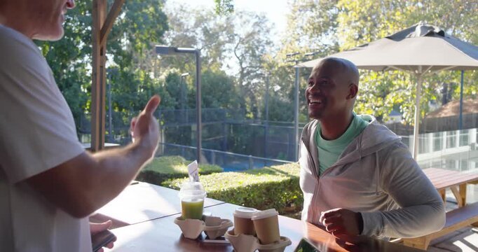 African American man paying on patio as senior server handing reader tapping card lifting carrier