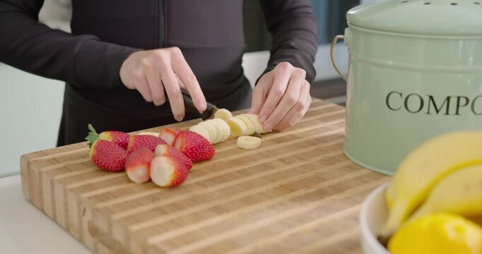 Male at kitchen counter preparing fruit, slicing banana on board, finishing row then peeling banana