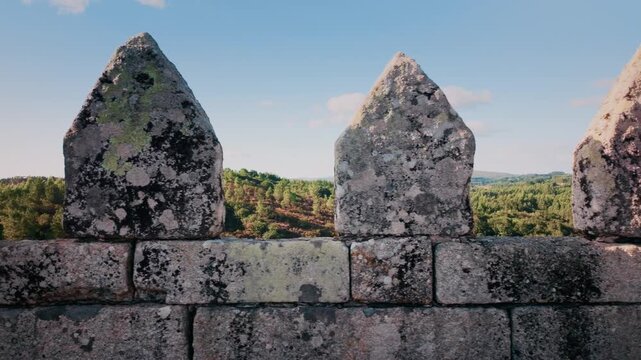 Majestic stone merlons of the medieval Pambre Castle in Galicia, Spain, with a lateral camera movement revealing the fortress crenellations and the lush green valley in the background