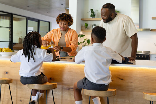 African American family preparing breakfast at kitchen island with mixing spoon and bananas