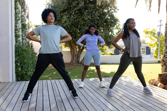 African American friends standing in wide-stance pose on backyard deck wearing sneakers and tracker