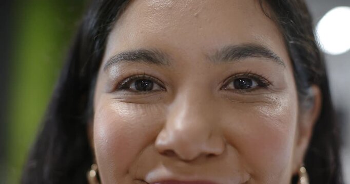 Adult woman facing lens, blinking and smiling while camera starting recording in studio, gold hoops