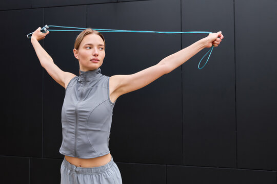 Young woman warming up with a jump rope in an urban city landscape