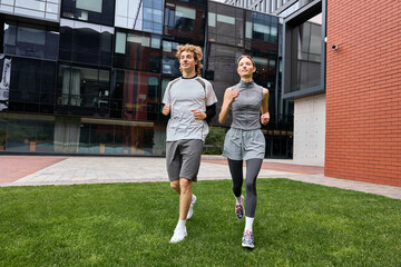 Obraz premium Young couple enjoys morning jog near modern office building in the city
