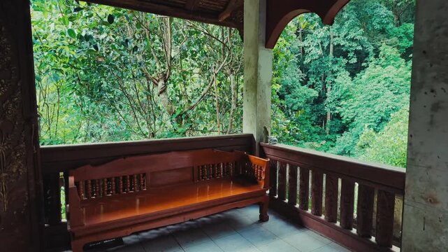 Wooden bench on peaceful veranda overlooking lush tropical jungle landscape, Quiet terrace surrounded by rainforest greenery creating relaxing nature retreat atmosphere 4k