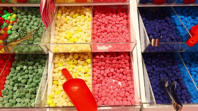 Children selecting candy from organized display bowls with sorted confectionery colors in store environment
