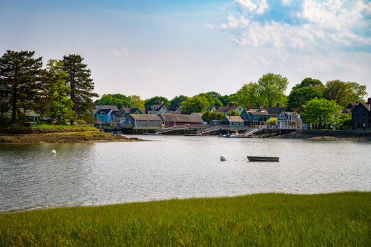 Colorful waterfront buildings and a small boat on the Piscataqua River in Portsmouth, New Hampshire, viewed from Peirce Island on a sunny day.