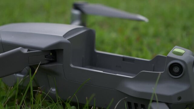 Gray quadcopter battery extraction detail on grass