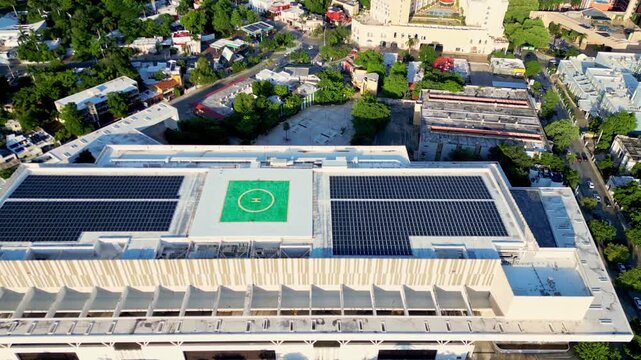 Aerial view of solar panels and helipad on a hospital roof in the city
