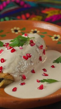 Poblano pepper stuffed with picadillo covered in creamy nogada sauce and pomegranate seeds