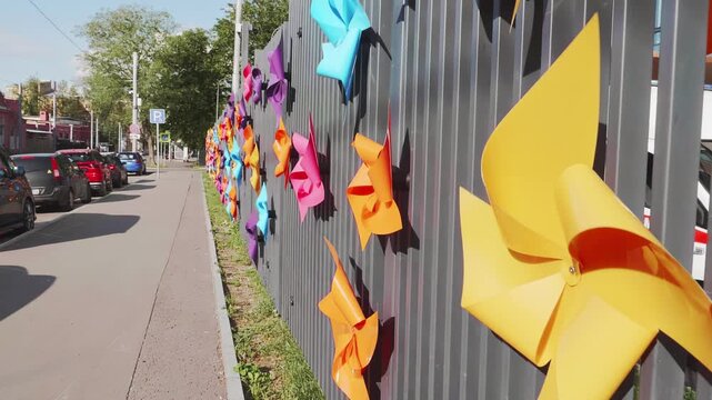 Colorful Plastic Pinwheels on a Metal Fence in the City