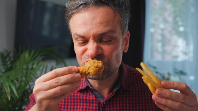 Junk food advertisement concept. Man eating fried chicken, enjoying fast food.