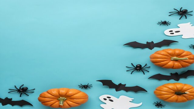 Halloween flat lay with pumpkins, bats, ghosts and spiders on blue background