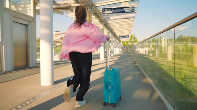 Caucasian woman pulling a suitcase and running, late for flight. 