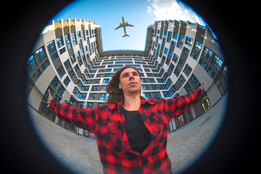 Inspired man standing with arms wide open under flying airplane with copy space
