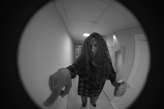 Monochromatic door peephole view of dangerous intruder ringing doorbell with copy space