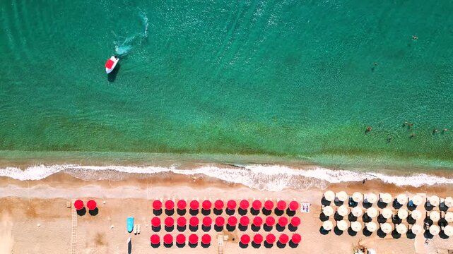 Top-down view of sandy beach with sun umbrellas and turquoise sea water