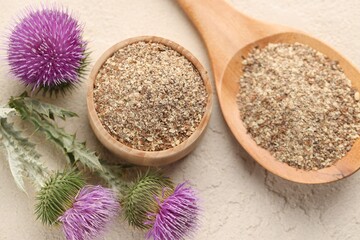 Fototapeta premium Ground milk thistle seeds and flowers on light table, flat lay