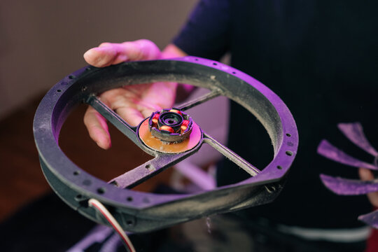 Close-up view of hand holding dusty disassembled cooling fan. Focus on brushless motor with copper windings. Concept for computer repair, maintenance, electronic hardware cleaning.