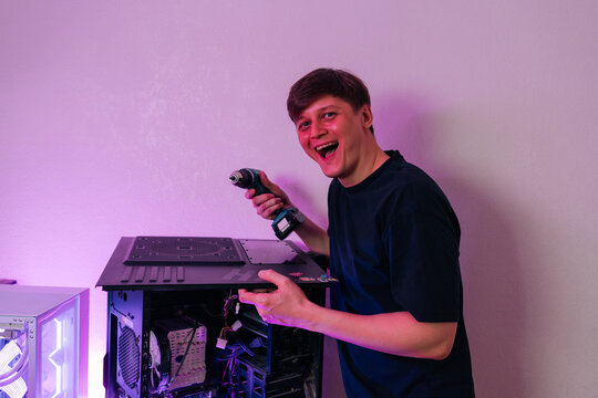 Man laughing excitedly while holding cordless drill, assembling or customizing high performance gaming desktop computer with visible internal component setup.