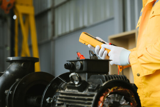 Conceptual engineering technician in industrial plants. Focused worker inspecting machinery with meter to ensure peak performance