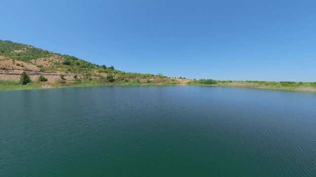 Cinematic flying over a mountain pond close to the water