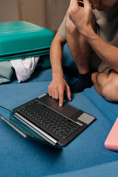Cropped shot of pensive tourist connecting to internet and typing personal information on a laptop for travel arrangements, making reservations, or managing bookings before a trip.