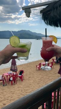 Cheers with Caipirinha Cocktails on a Tropical Beach in Ilhabela, Brazil