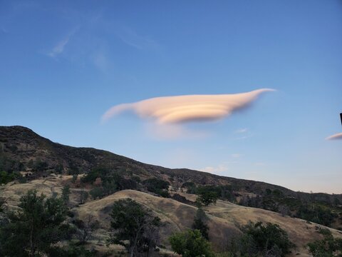Lenticular cloud over rolling hills at dusk