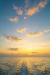 Fototapeta premium Wide view of ocean water under yellow sunset sky. Boat wake creates trail on sea surface towards horizon. Calm waves, soft clouds create peaceful seascape. Tropical landscape with blue, orange