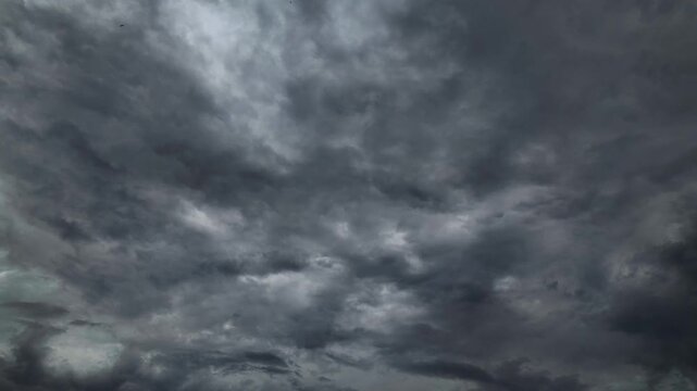 4K timelapse of grey overcast storm clouds moving across sky. Moody dramatic cloudscape background video. Weather forecast and atmospheric nature footage.