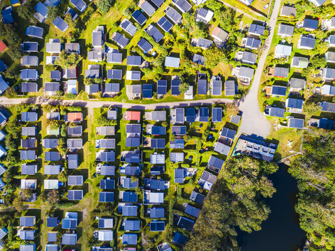 Aerial view of Skrea strand holiday park featuring rows of small cabins, green lawns, and nearby trees in Falkenberg, Halland County, Sweden.
