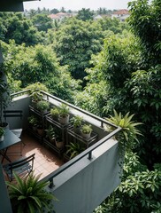 Obraz premium Modern balcony with many potted plants overlooks tropical forest. Small garden furniture sits on tiled floor near green ferns. Scenic view of dense trees, distant houses under bright sky. Peaceful