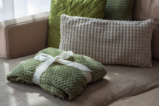 Cozy Textured Green Blanket Tied With White Ribbon On Sofa With Cushions