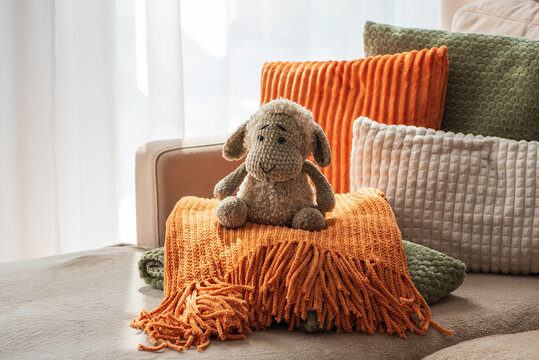 Cozy Autumn Scene With Stuffed Sheep Toy And Textured Cushions On Sofa