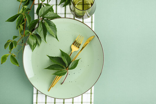 Elegant Thanksgiving Dinner Table Setting with Golden Cutlery and Green Leaves Accent